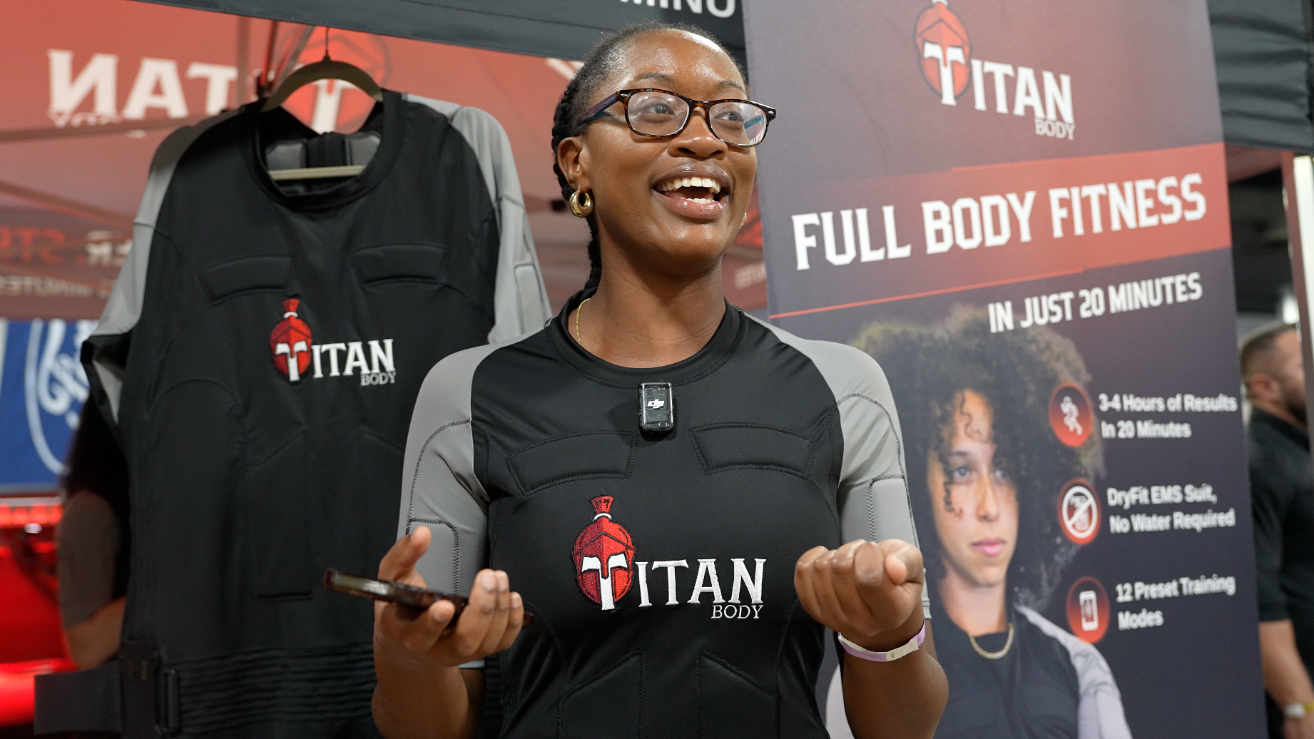 A woman with her phone in hand and a TitanBody fitness suit on at the Miami International Fitness Expo.