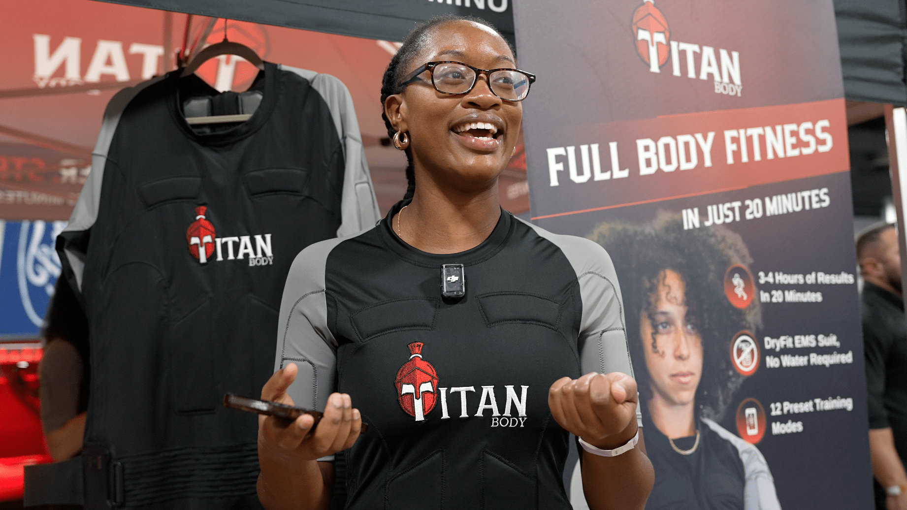 A woman with her phone in hand and a TitanBody fitness suit on at the Miami International Fitness Expo.