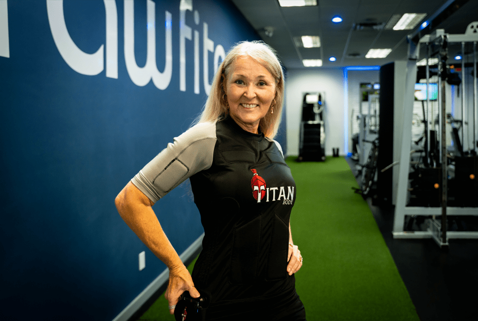 Woman wearing a TitanBody EMS suit smiling in a gym